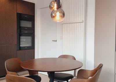 Moderne keukenhoek met ronde eettafel, designstoelen en ingebouwde toestellen