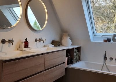 Lichtrijke badkamer met bad onder dakraam en moderne kranen